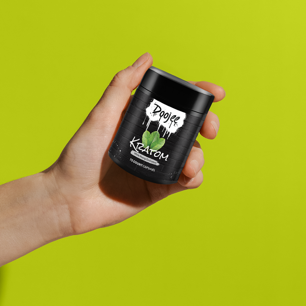 A hand holding a bottle of 'Doojee Kratom' capsules against a green background.